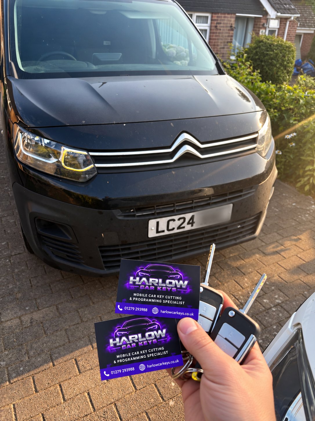 Two brand new keys supplied for a 2024 Citroën Berlingo in Hoddesdon after all keys were lost, held in front of the van with Harlow Car Keys business cards